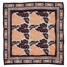 Floral patterned batik bandana with orange and black flowers on a white background