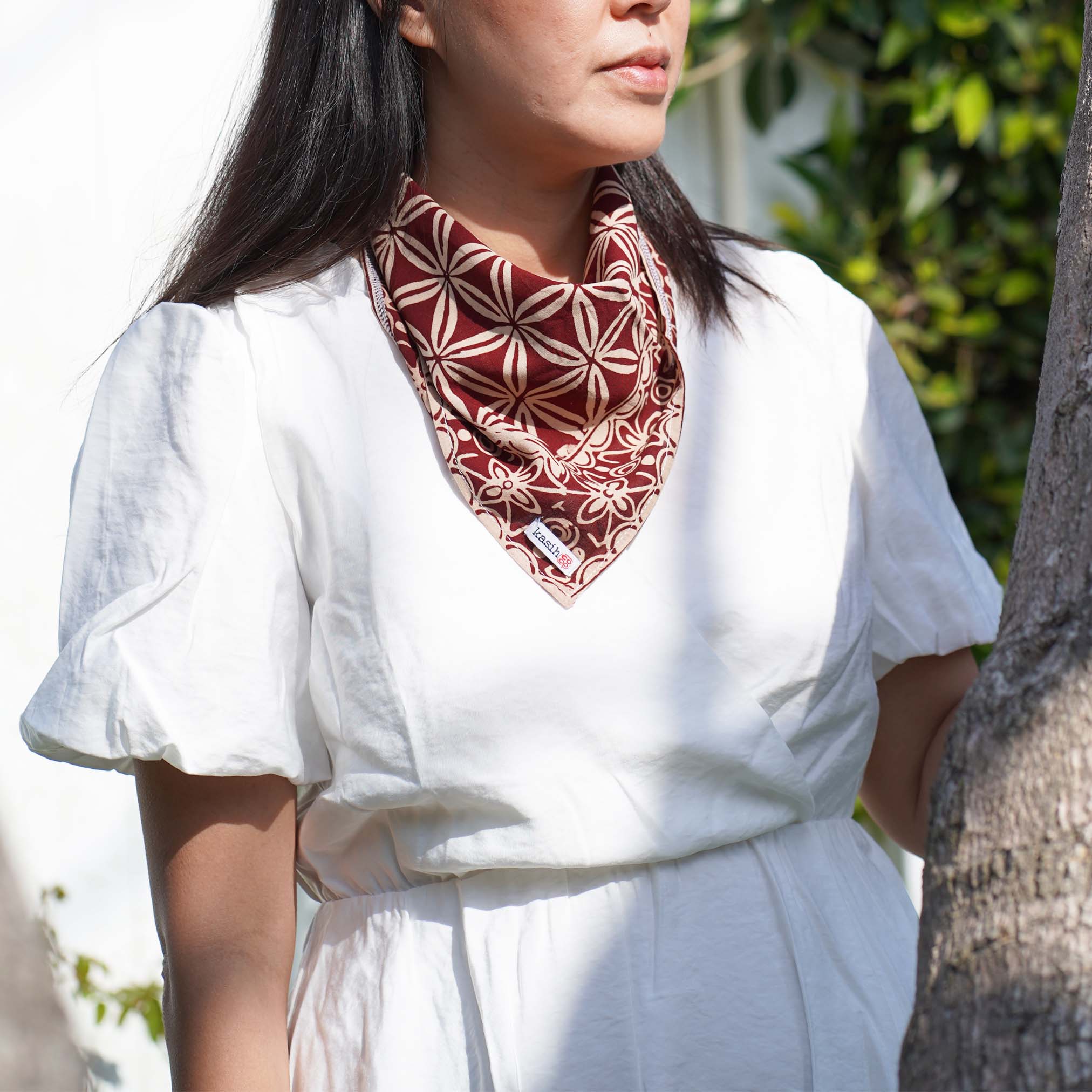 A person wearing patterned cotton bandana with geometric design on a brown background