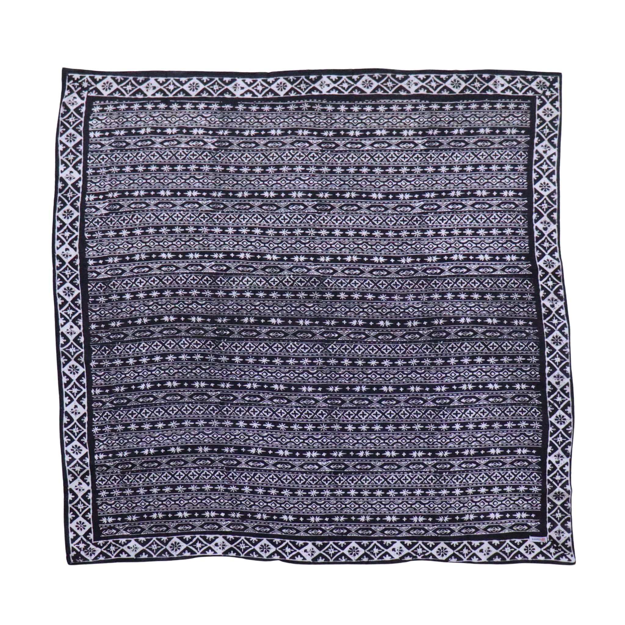 A large square-shaped batik bandana with a geometric black and white pattern, displayed flat.