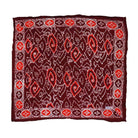 A large hand-dyed batik bandana in shades of red and orange with geometric patterns, displayed flat.