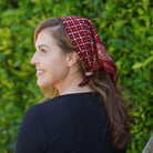 Woman wearing a red patterned headscarf against a green leafy background