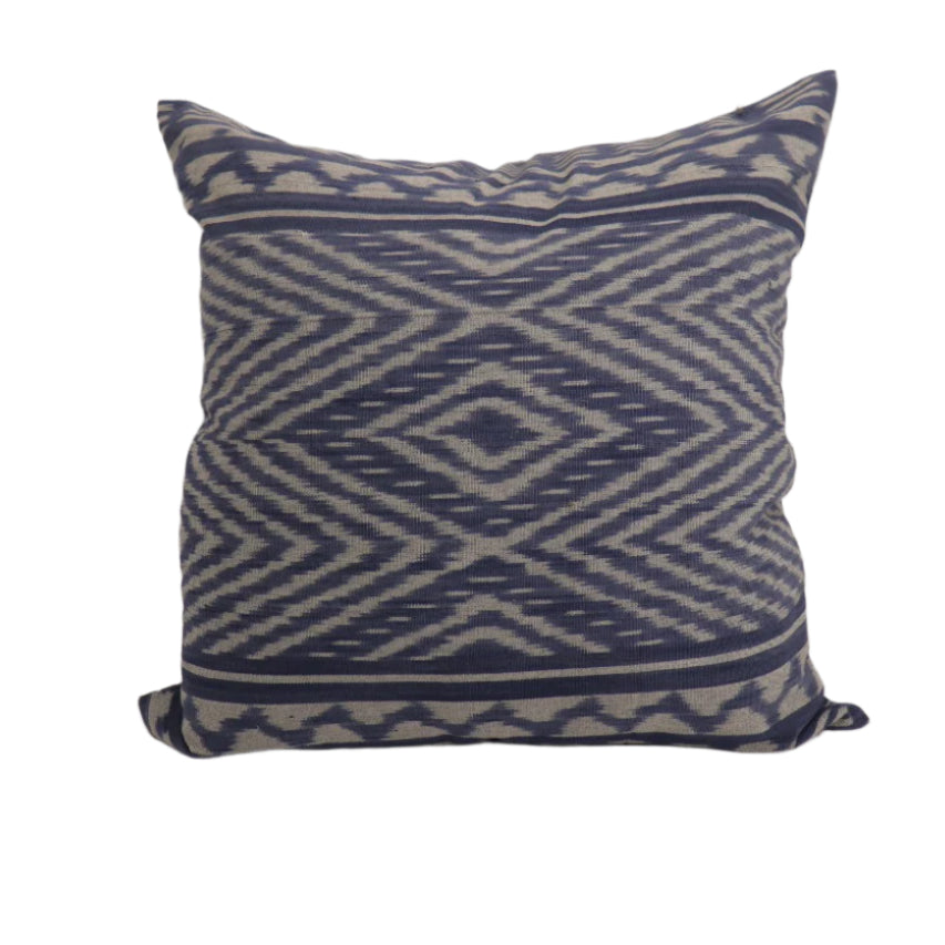 Decorative hand woven ikat pillow with blue and white pattern on a plain background