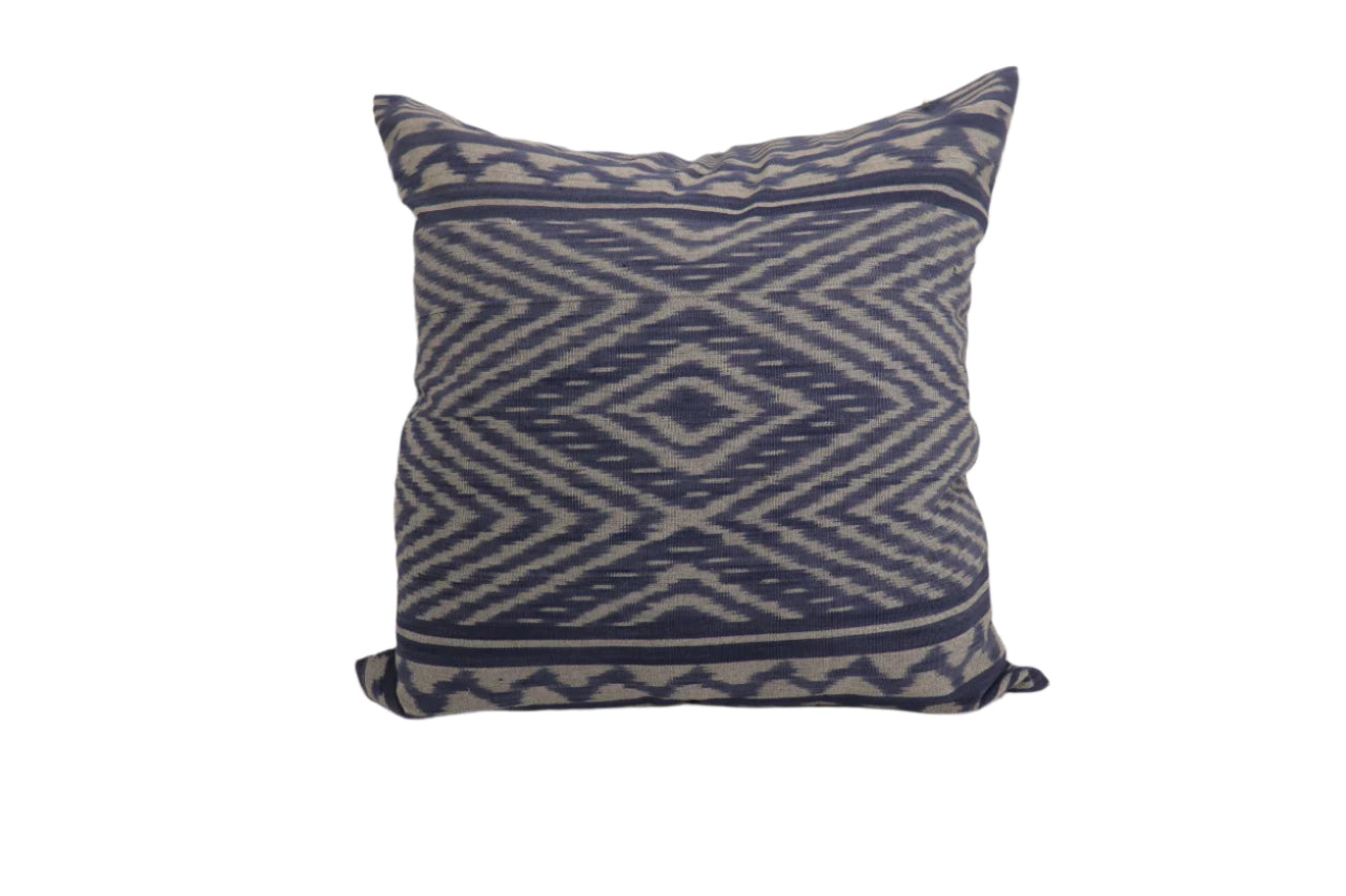 Decorative hand woven ikat pillow with blue and white pattern on a plain background