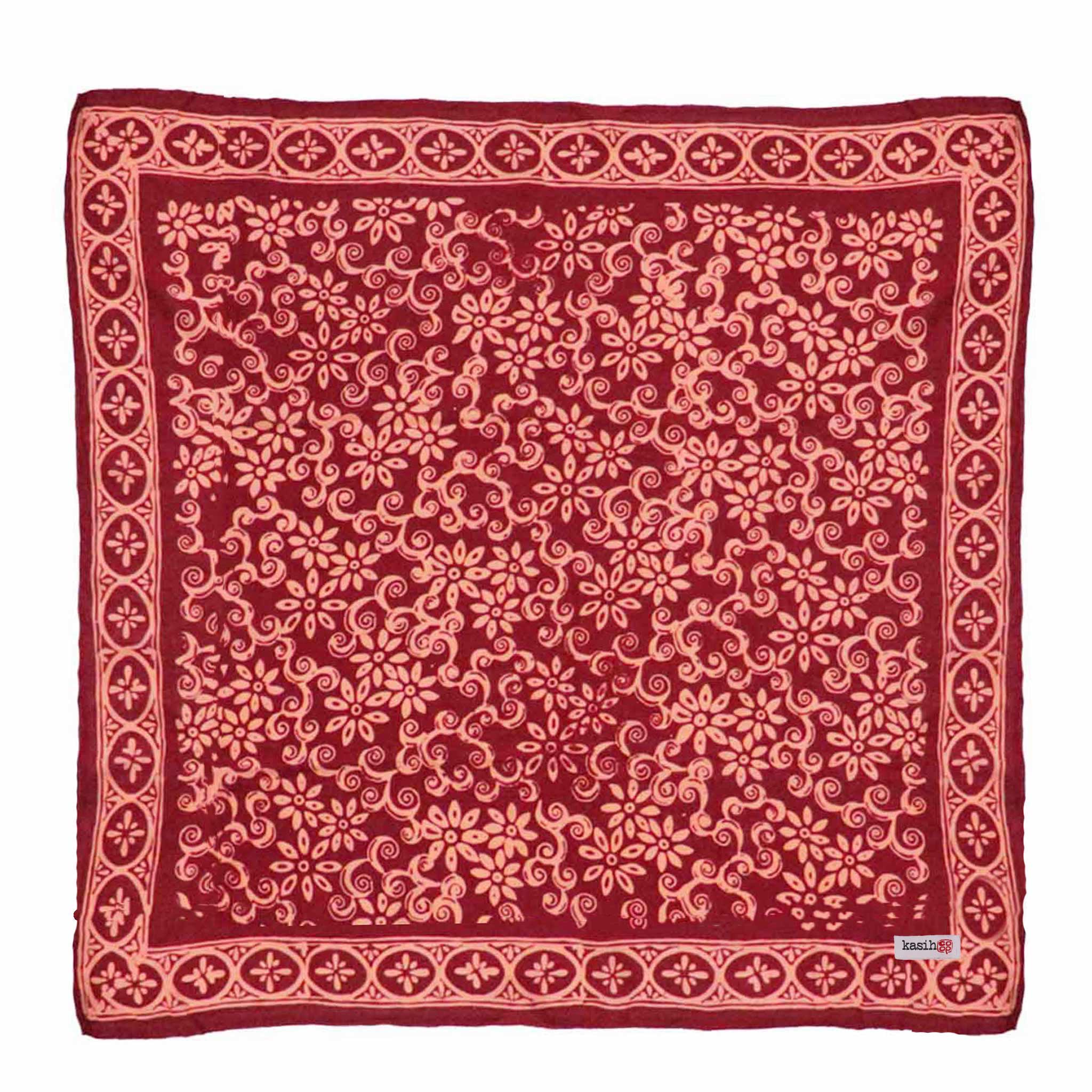 Red hand dyed hand made batik bandana with intricate pink patterns on a white background