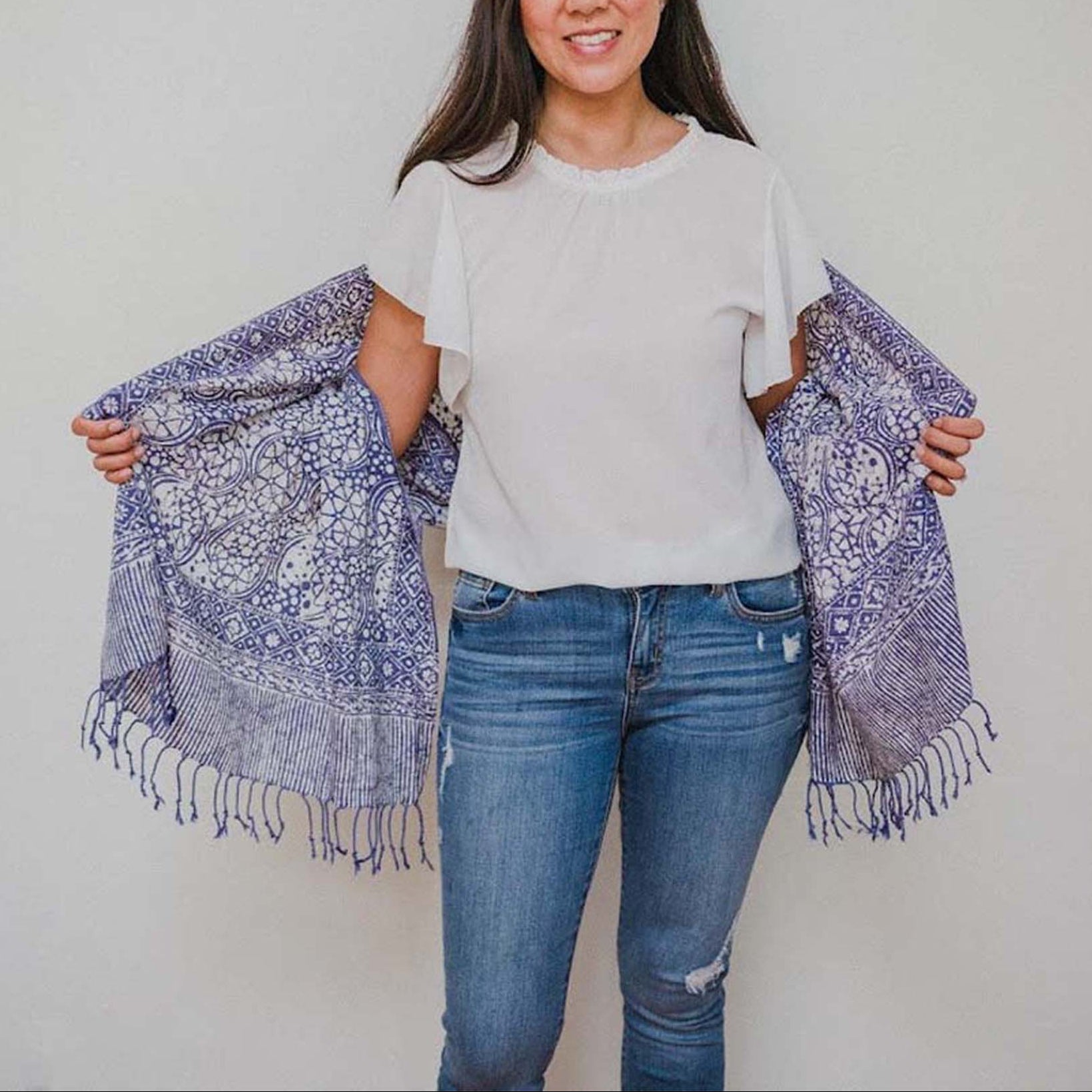 Woman holding a blue patterned scarf against a plain background