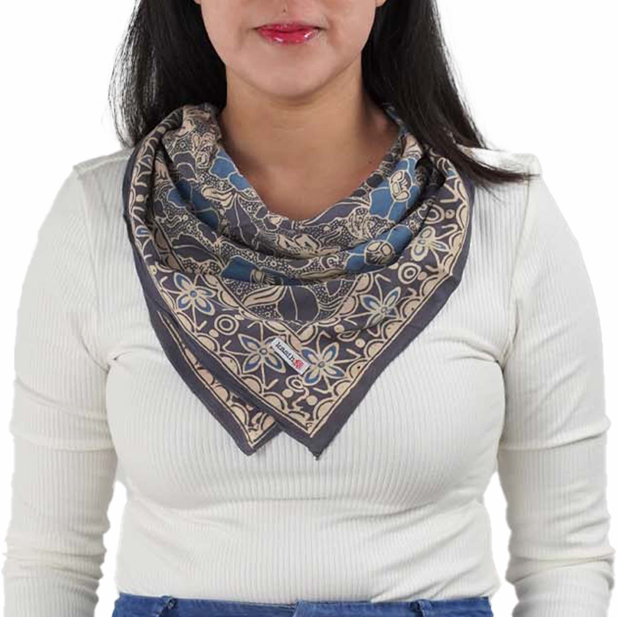 A person wearing a gray and blue hand-dyed batik bandana with a floral pattern around their neck.