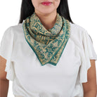 Woman wearing a green and teal patterned scarf on a white background